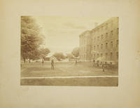 image of Photograph of a doubles lawn tennis match, with 2 observers and a large brick building and