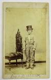 RARE CARTE DE VISITE OF DWARF JOHN MCGUIRE STANDING NEXT TO AN ORNATE CHAIR WHILE WEARING A SUIT AND TOP HAT AND HOLDING A CANE IN HIS HAND