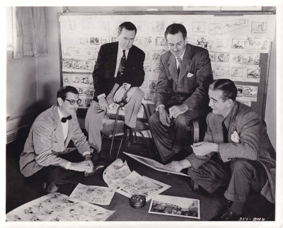 Burbank, CA: Walt Disney, 1951. Vintage publicity photograph of producer Walt Disney, writers Erdman...