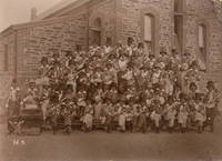 A group photograph of young lads in blackface, dressed as minstrels with banjos