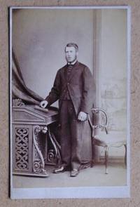 Carte De Visite Photograph: Portrait of a Man Standing Betwwen a Desk & Chair.