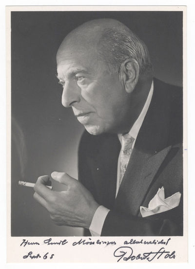 Bust-length photograph of the noted Austrian composer and conductor in formal attire, cigarette in hand, signed, inscribed "Herrn Emil Mösslinger allerherzlichst," and dated September [19]65