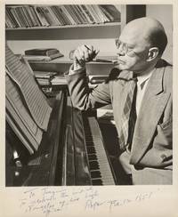 Photograph of Sessions seated at the piano, pen in hand, with sheets of manuscript paper before him. Signed and inscribed to fellow composer Joaquín Nin-Culmell